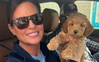 Woman holding a beige Cavapoo puppies inside a car