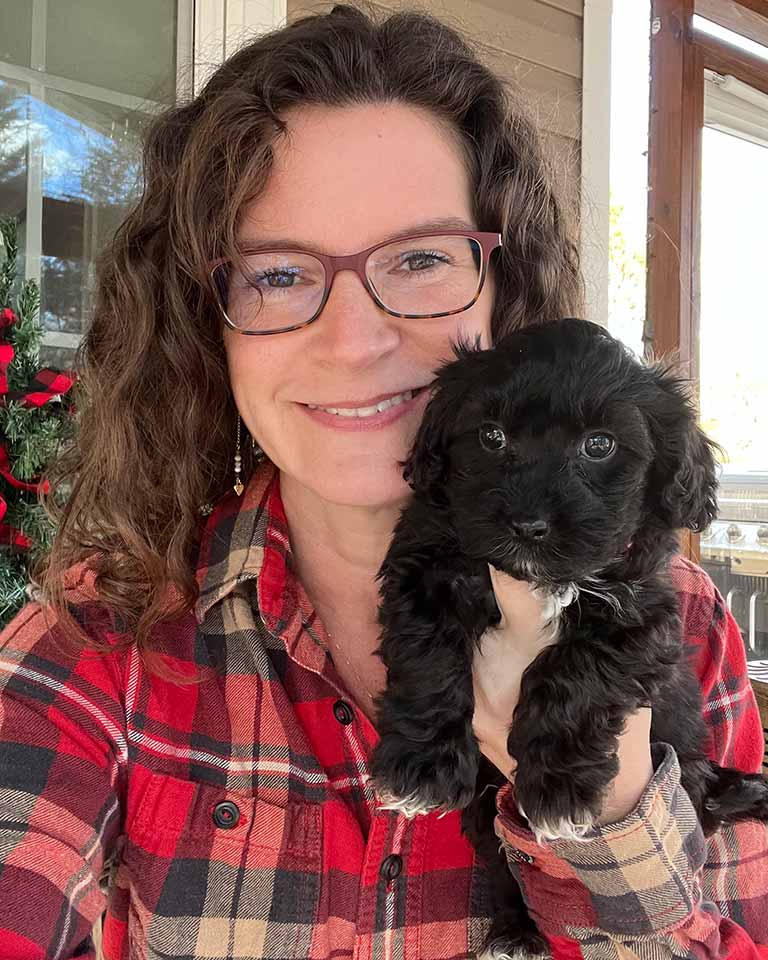 Owner of Jones Farm Puppies holding a black Cavapoo puppy in her arms