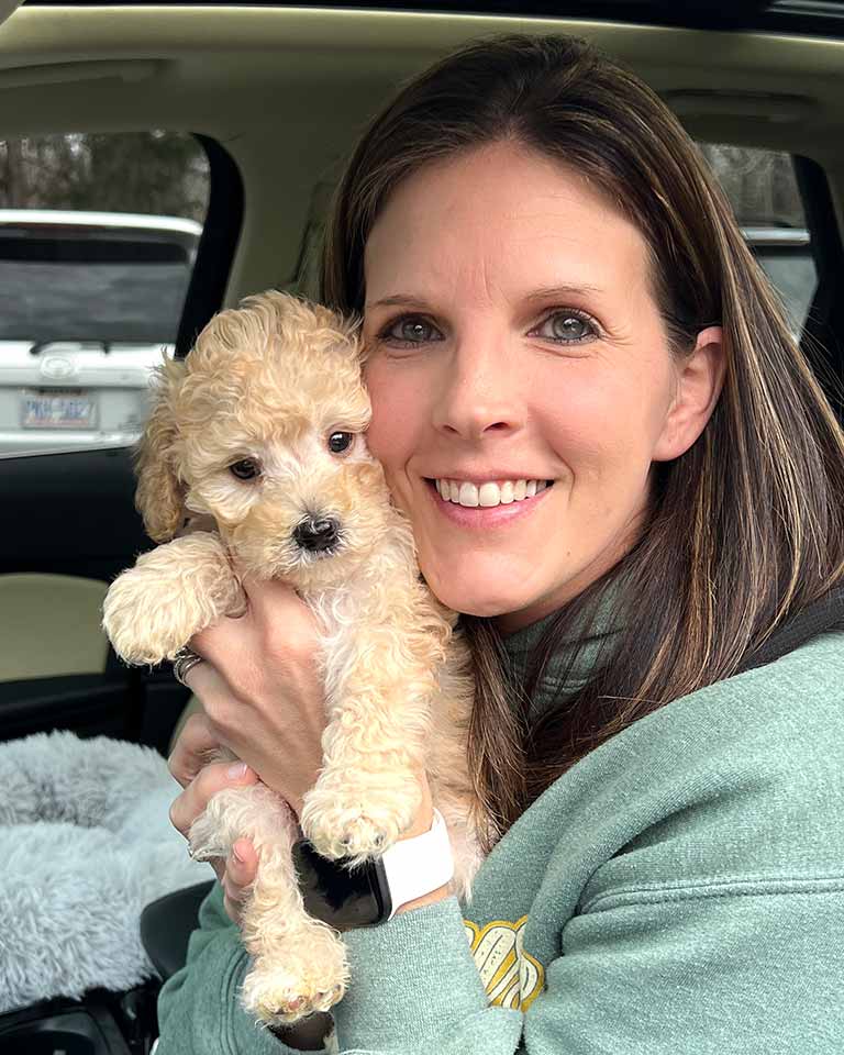 Woman holding a white Cavapoo puppy