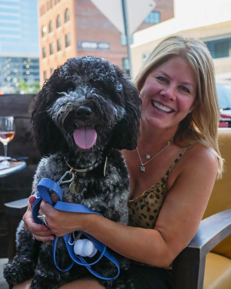 Woman sitting down and hugging an adult black dog