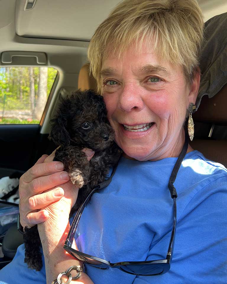 Woman holding a blacl Cavapoo puppy in her hands