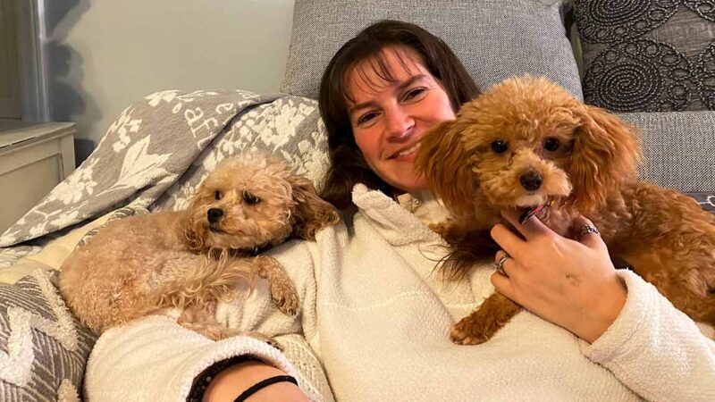 woman laying down with 2 puppies o each side