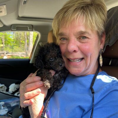 Woman holding a black puppy with good Cavapoo temperament