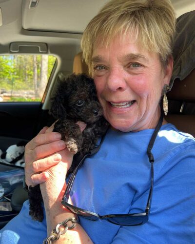 Woman holding a black Cavapoo in her arms